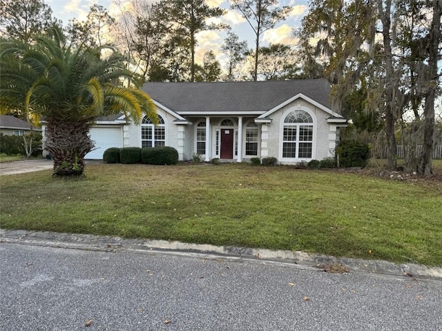 ranch-style house featuring a garage and a yard