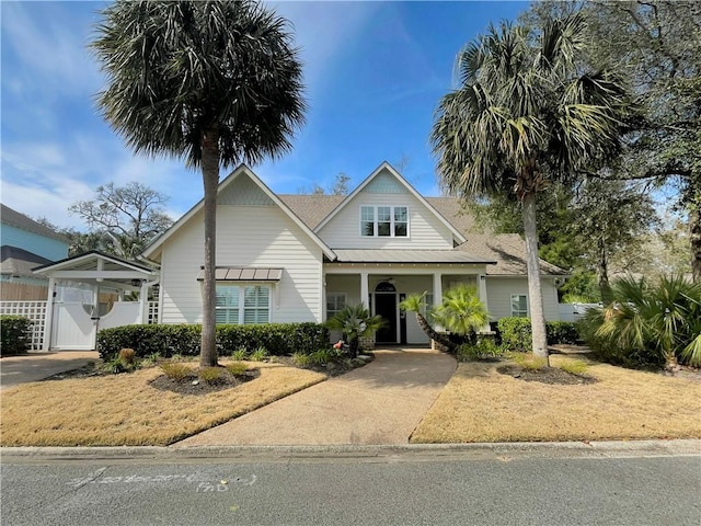 view of front facade featuring concrete driveway, fence, and a gate