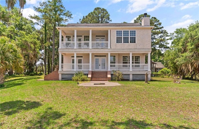 1889 Eagle Neck Dr NE, Townsend, GA 31331 - view of front of property featuring french doors, a chimney, covered porch, a front yard, and stucco siding