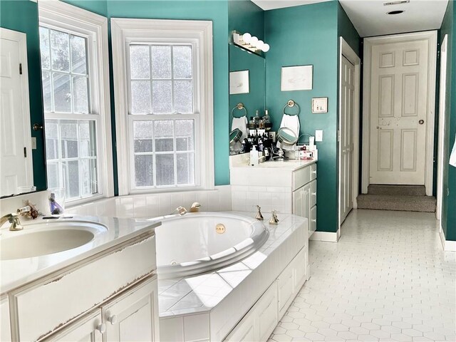 bathroom featuring a relaxing tiled tub and vanity