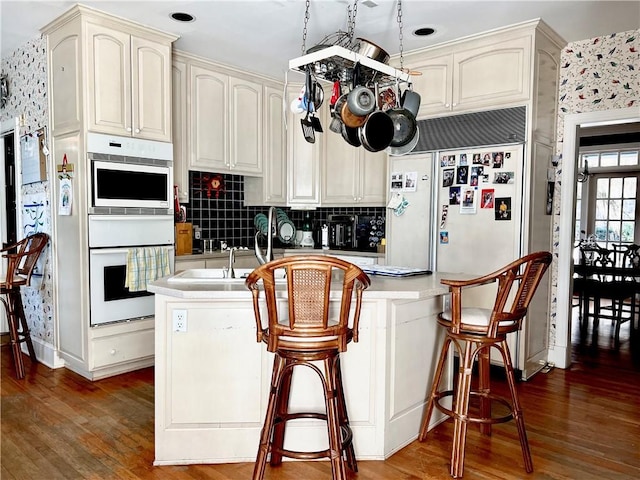 kitchen with tasteful backsplash, dark hardwood / wood-style floors, kitchen peninsula, and double oven