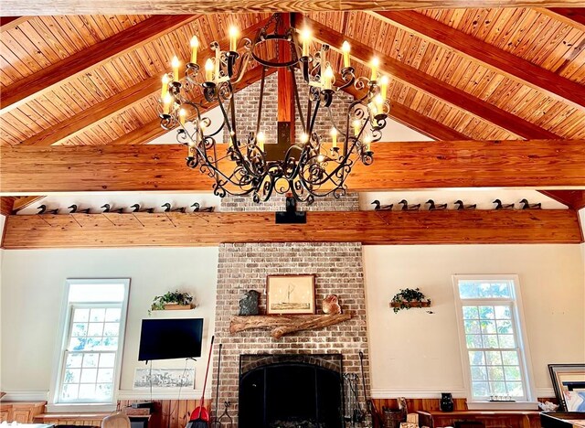 living room with a fireplace, vaulted ceiling with beams, an inviting chandelier, and a wealth of natural light