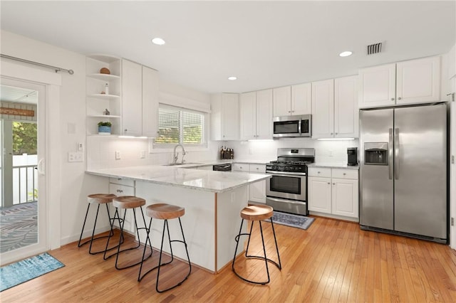 630 Sheraton Plz, Saint Simons Island, GA 31522 - kitchen featuring appliances with stainless steel finishes, a peninsula, a breakfast bar area, white cabinetry, and recessed lighting