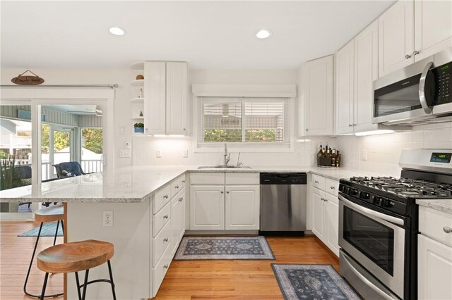 630 Sheraton Plz, Saint Simons Island, GA 31522 - kitchen with appliances with stainless steel finishes, a peninsula, a kitchen breakfast bar, white cabinets, and recessed lighting