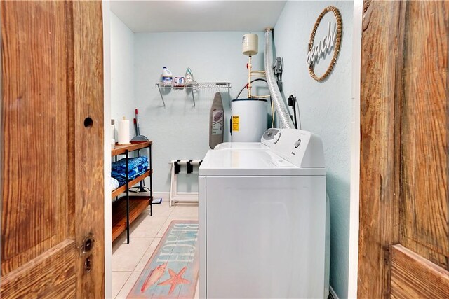 clothes washing area featuring water heater, laundry area, washing machine and dryer, and light tile patterned flooring