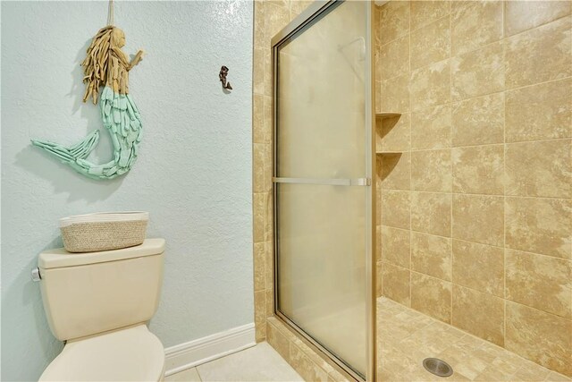 full bathroom featuring a shower stall, toilet, a textured wall, and tile patterned floors