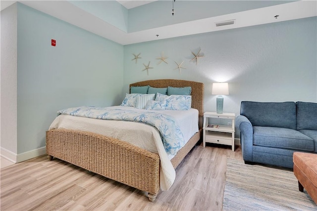 bedroom with visible vents, wood finished floors, and baseboards