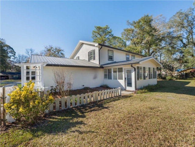 rear view of house featuring a sunroom and a yard