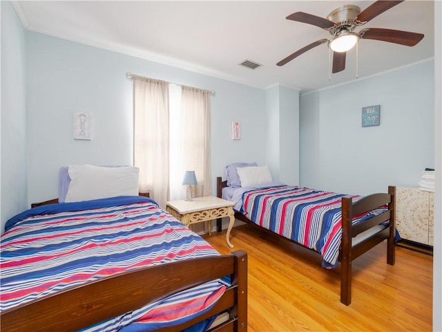 bedroom featuring hardwood / wood-style flooring, ceiling fan, and ornamental molding