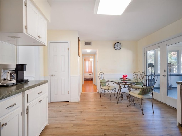 kitchen featuring white cabinets, light hardwood / wood-style floors, dark stone countertops, and french doors