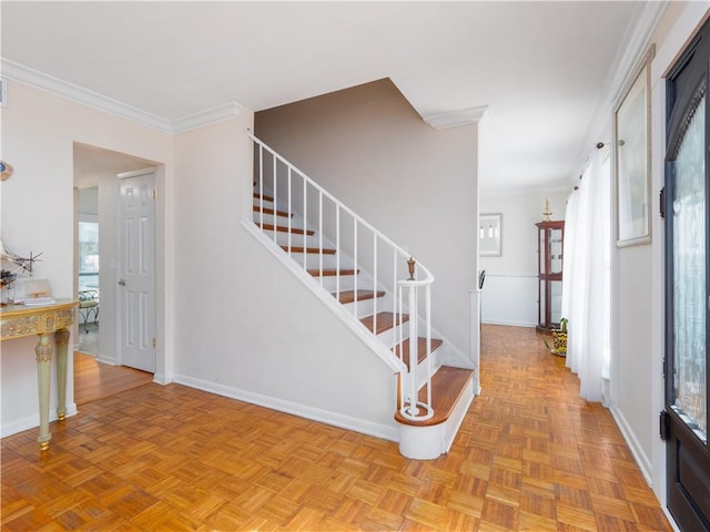 stairway with crown molding and parquet flooring