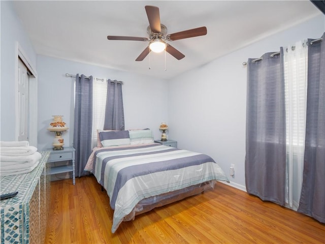 bedroom with multiple windows, a closet, light hardwood / wood-style floors, and ceiling fan