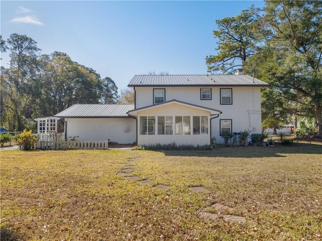 rear view of property featuring a sunroom and a lawn