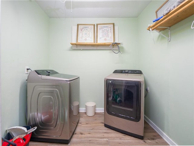 washroom with light hardwood / wood-style floors and washing machine and dryer