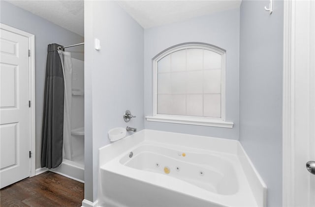 bathroom featuring a whirlpool tub, wood finished floors, and a shower with curtain