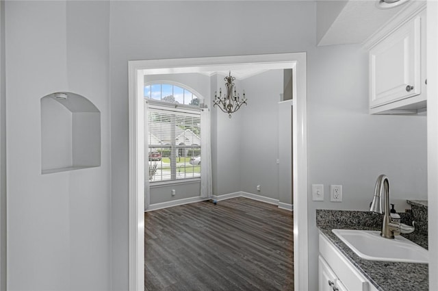 interior space with baseboards, a sink, dark wood-style flooring, and a chandelier