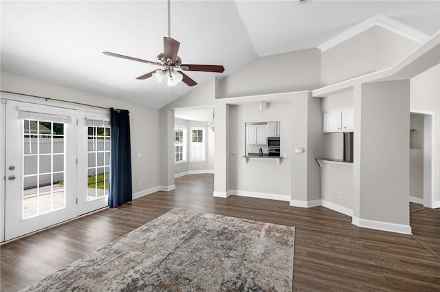 unfurnished living room with baseboards, ceiling fan, dark wood-style floors, and vaulted ceiling