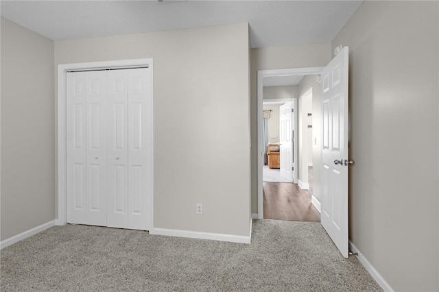 unfurnished bedroom with carpet flooring, baseboards, and a closet