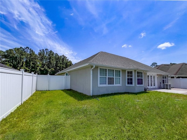 rear view of house featuring a lawn, a fenced backyard, and french doors