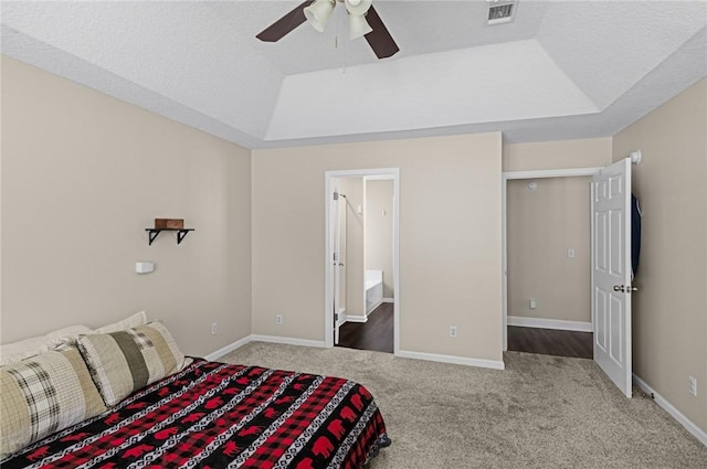bedroom with carpet floors, visible vents, baseboards, ceiling fan, and a tray ceiling