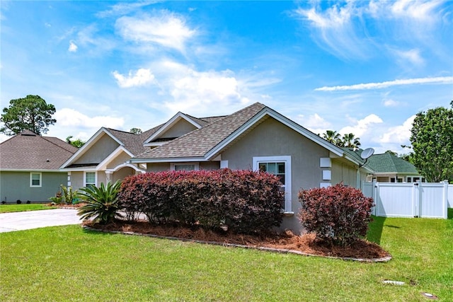 ranch-style house with stucco siding, fence, a shingled roof, and a front lawn