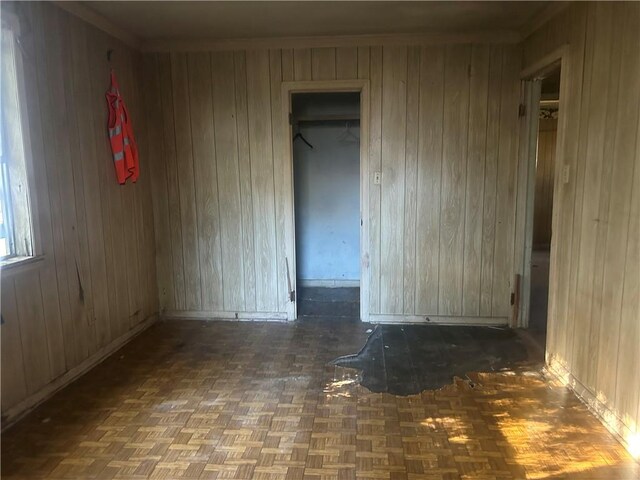 empty room with dark parquet flooring and wooden walls