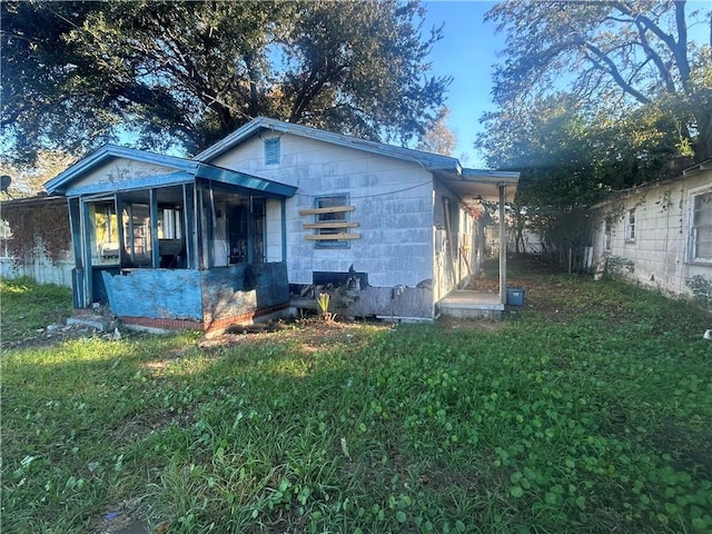 rear view of house featuring a sunroom and a yard