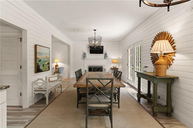 101 Settlers Rd, Saint Simons Island, GA 31522 - dining room with a fireplace, wooden walls, light wood-style floors, and a chandelier