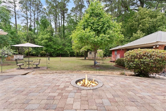 view of patio with an outdoor structure, a shed, and an outdoor fire pit
