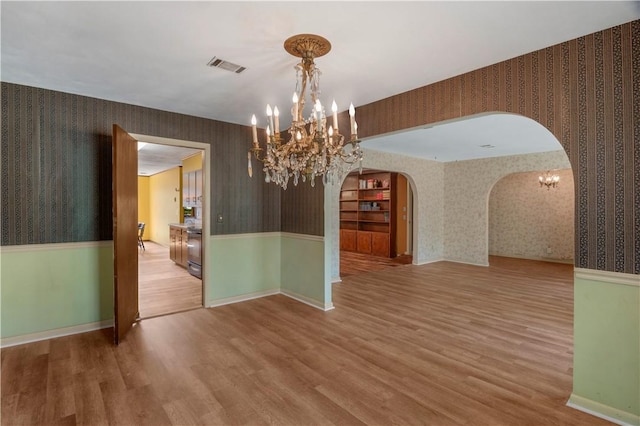 208 Plantation Dr, Waycross, GA 31501 - unfurnished dining area with arched walkways, wallpapered walls, visible vents, and a chandelier