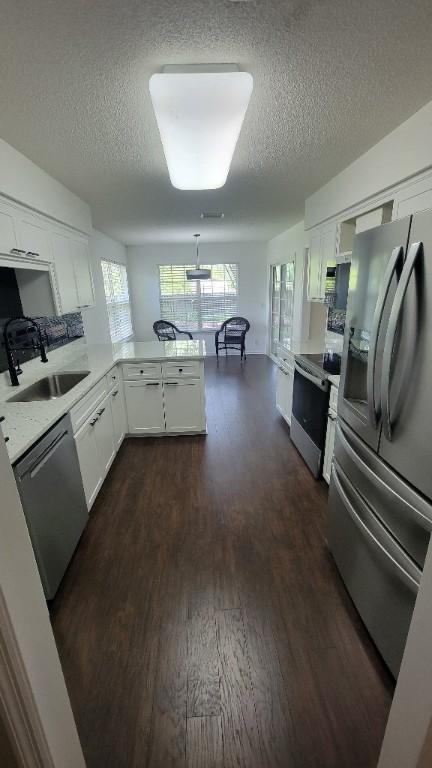 102 Norwood Ct, Brunswick, GA 31525 - kitchen with appliances with stainless steel finishes, a textured ceiling, dark wood-style flooring, white cabinetry, and light countertops