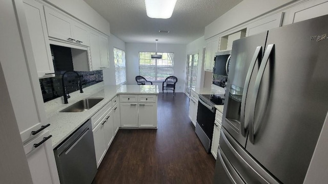 102 Norwood Ct, Brunswick, GA 31525 - kitchen with appliances with stainless steel finishes, a peninsula, dark wood finished floors, white cabinets, and hanging light fixtures