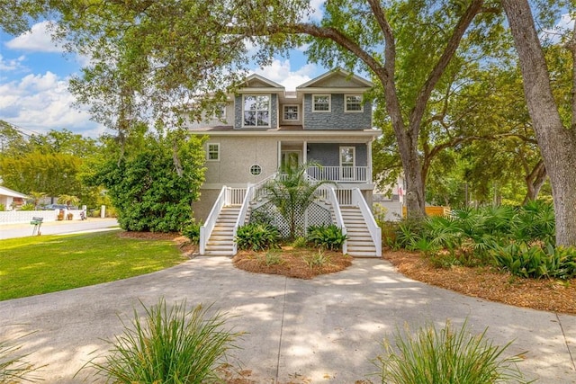 200 Colgana Way, Saint Simons Island, GA 31522 - coastal home with stairway, a porch, a front yard, and stucco siding