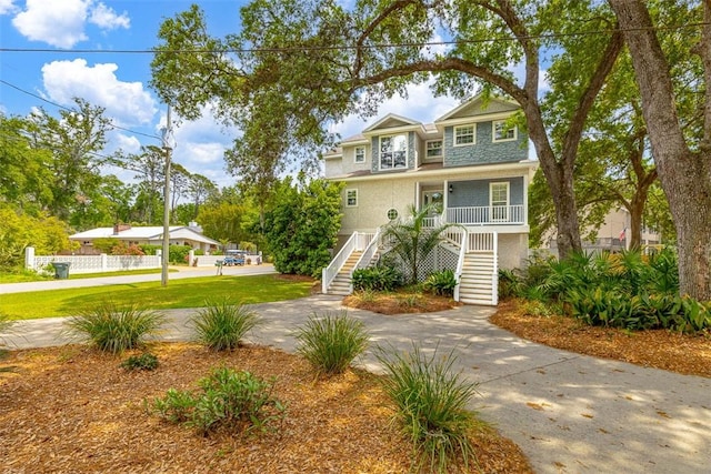 200 Colgana Way, Saint Simons Island, GA 31522 - coastal inspired home featuring stairway, covered porch, a front lawn, and stucco siding