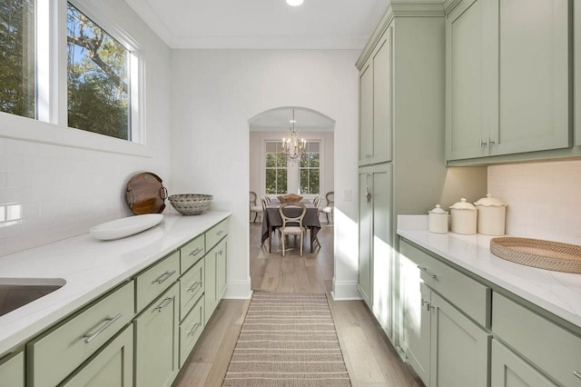 kitchen featuring tasteful backsplash, light stone countertops, green cabinets, and light wood-type flooring