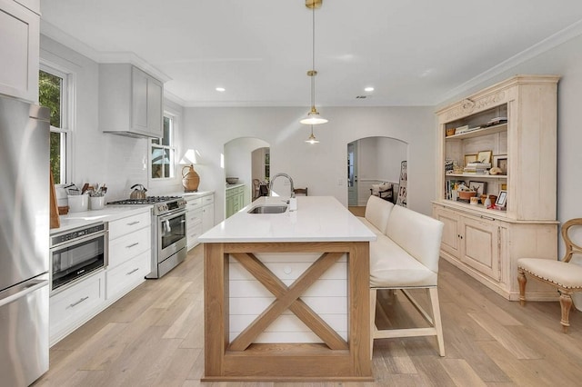 kitchen featuring pendant lighting, sink, white cabinets, stainless steel appliances, and light wood-type flooring