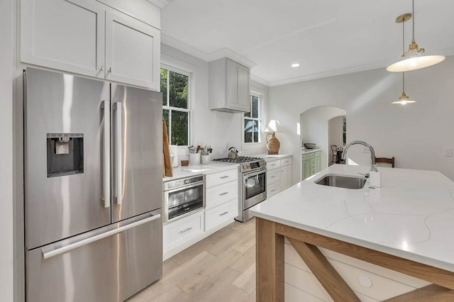 kitchen featuring sink, pendant lighting, stainless steel appliances, light stone countertops, and white cabinets