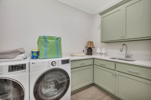 clothes washing area with sink, washer and clothes dryer, cabinets, ornamental molding, and light wood-type flooring