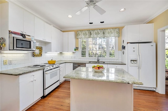 kitchen featuring stainless steel appliances, light stone countertops, a kitchen island, and white cabinets