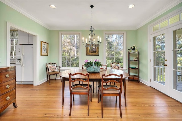 dining area with an inviting chandelier, a wealth of natural light, light hardwood / wood-style flooring, and ornamental molding