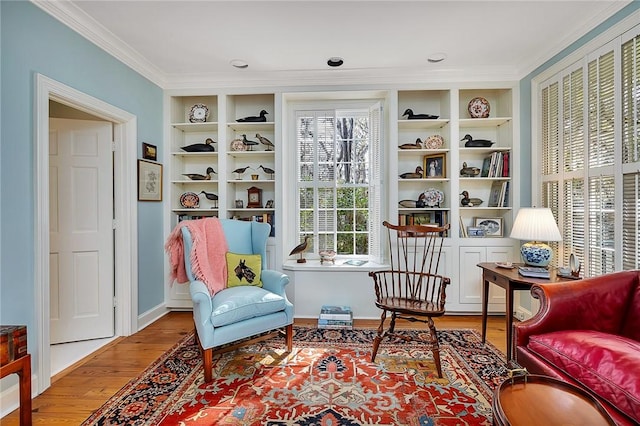 sitting room with crown molding, light hardwood / wood-style flooring, and built in shelves