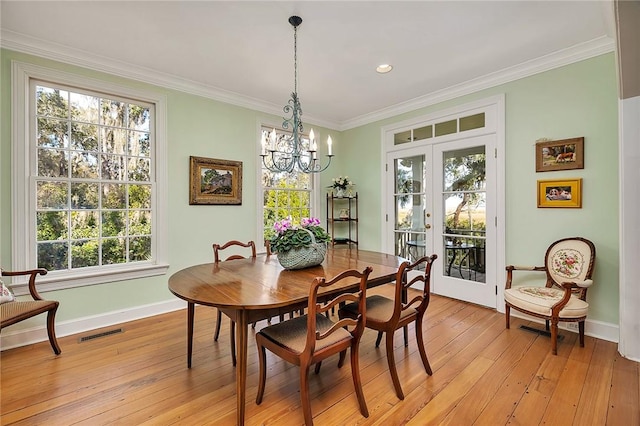 dining space featuring ornamental molding, french doors, and light wood-type flooring