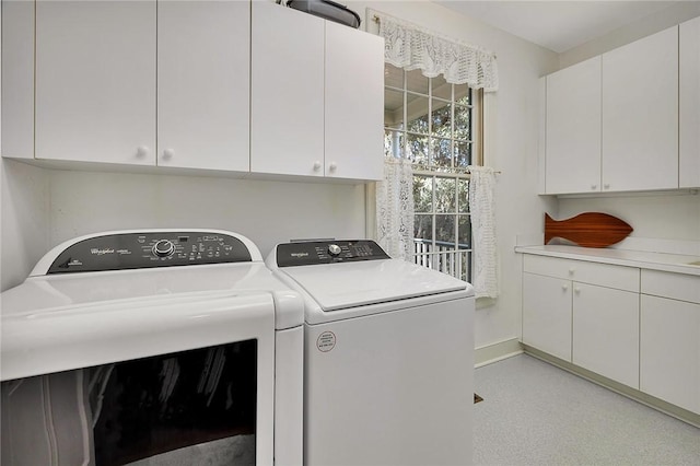 clothes washing area with cabinets and washing machine and dryer