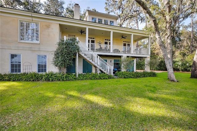 back of property with a yard and ceiling fan