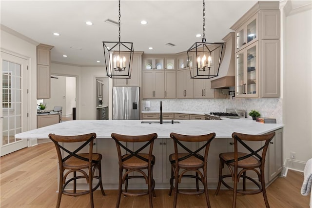 kitchen with pendant lighting, sink, stainless steel appliances, and light hardwood / wood-style flooring