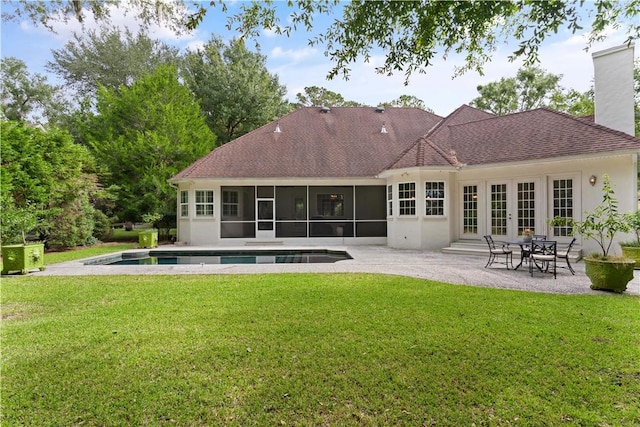 back of property with a lawn, a sunroom, a patio area, and french doors