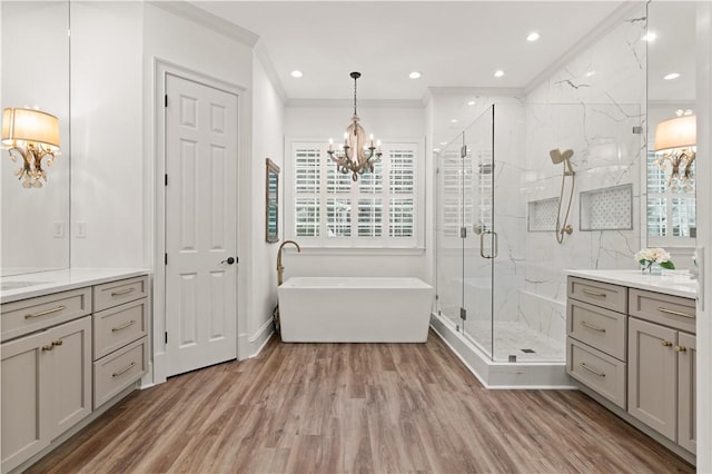 bathroom featuring vanity, hardwood / wood-style flooring, ornamental molding, independent shower and bath, and a notable chandelier