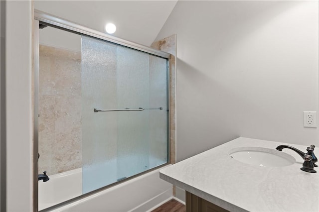 bathroom featuring sink, bath / shower combo with glass door, and vaulted ceiling