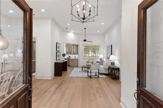 entryway featuring ceiling fan with notable chandelier, light wood-type flooring, and crown molding