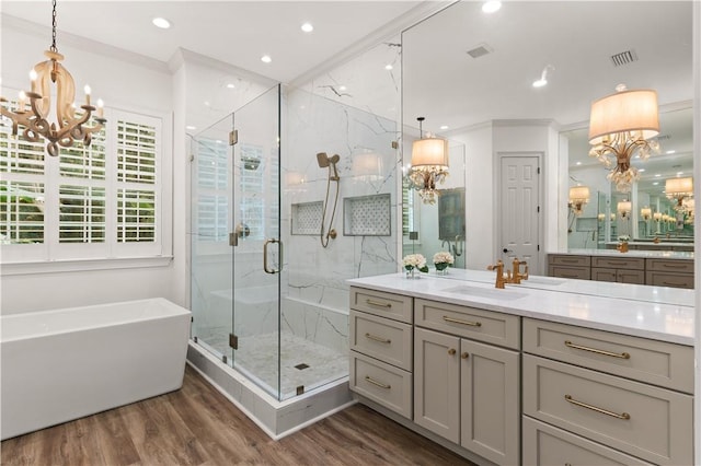 bathroom featuring vanity, an inviting chandelier, hardwood / wood-style flooring, ornamental molding, and independent shower and bath